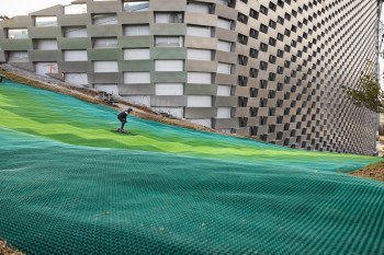 Die Piste führt an der Fassade des Industriegebäudes hinab ins Tal.