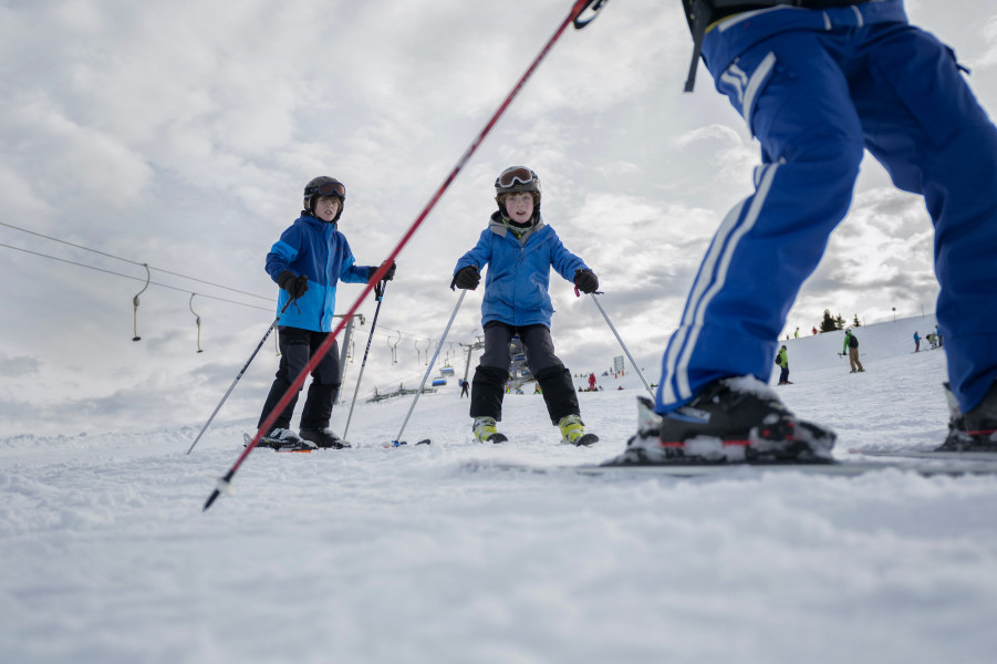 Kinder lernen das Skifahren mit spielerischen Übungen.