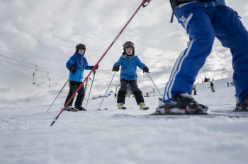 Kinder lernen das Skifahren mit spielerischen Übungen.