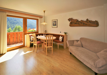 Schönes gemütliches Wohnzimmer mit großem ovalen Tisch, gepolsterter Eckbank, Couch und SAT-TV
