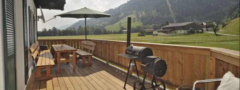 Schöne Holzterrasse mit Griller und Garten rund herum