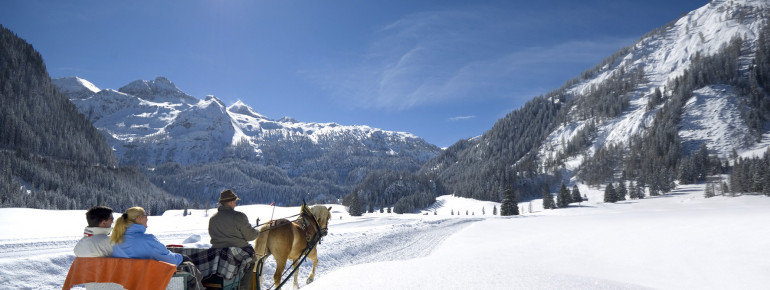 Mit dem Schlitten geht es auf der Passhöhe durch die verschneite Landschaft.