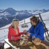 Zur Mittagspause gibt es eine Bünderplatte auf der Alpina Hütte mit Blick auf die FIS-Piste und die Luftseilbahn Piz Nair.